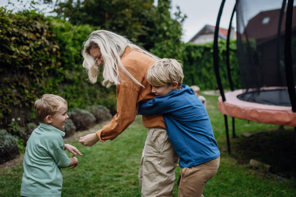 Mother having fun with sons in the garden, bonding moment. Concept of the Mother's Day, and motherly love.