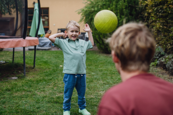 Father and son playing with ball outdoors, in the garden. Dad with little boy having fun outdoors.