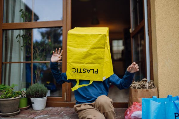 Boy put recycling bag for plastic waste on the head. Boy sorting the waste according to material into colored bags.