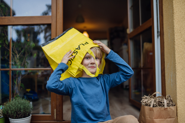 Boy put recycling bag for plastic waste on the head. Boy sorting the waste according to material into colored bags.