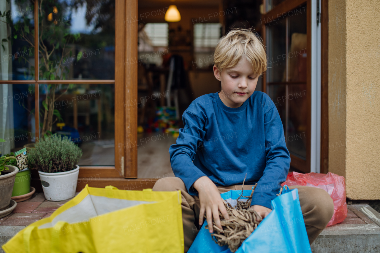 Boy kitchen waste, peel and leftover vegetables scraps into kitchen compostable waste. Boy sorting the waste according to material into colored bins, bags.