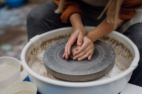 Close up woman making pottery on pottery wheel. Child creative activities and art. Boy making pottery with mom, having fun. Happy family moment.