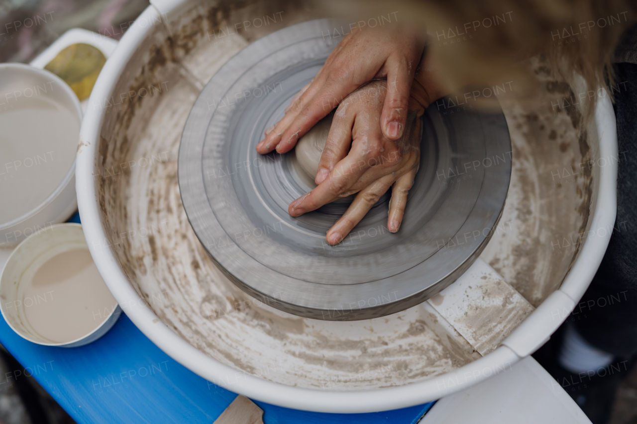 Close up of mother teaching son how to make pottery on pottery wheel. Child creative activities and art. Boy making pottery, having fun with mom. Happy family moment.