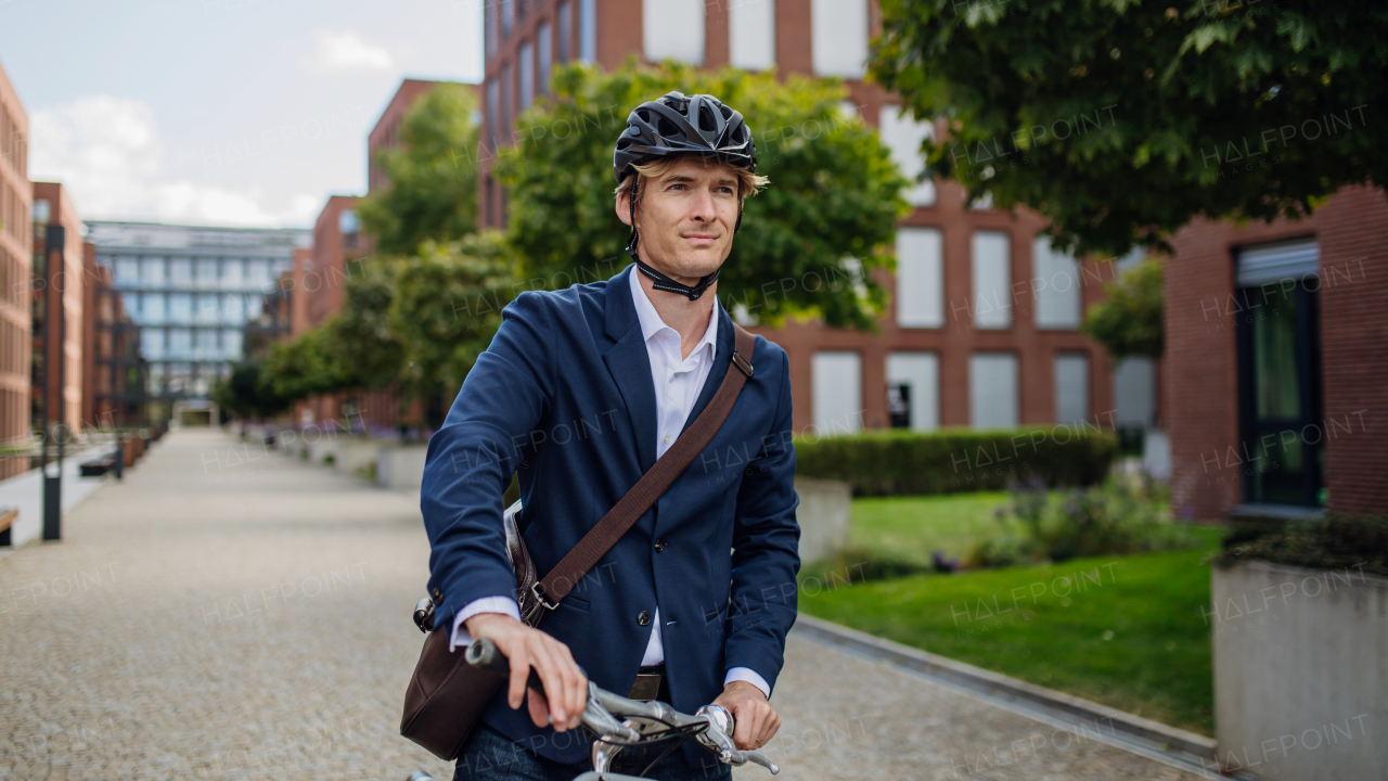 Handsome middle-aged man commuting through the city by bike in black suit. Male city commuter traveling from work by bike after a long workday.