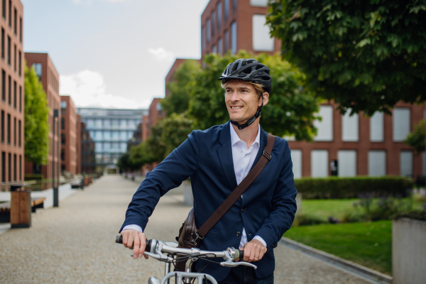 Handsome middle-aged man commuting through the city by bike in black suit. Male city commuter traveling from work by bike after a long workday.