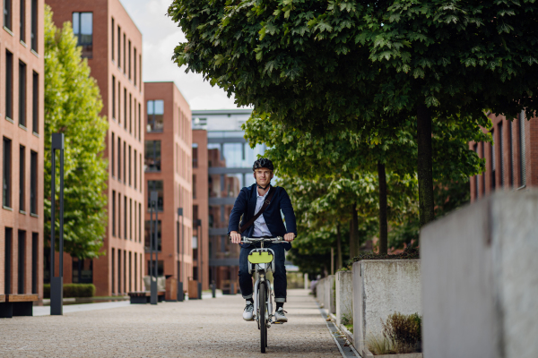 Handsome middle-aged man commuting through the city by bike, riding the bicycle. Male city commuter traveling from work by bike after a long workday.