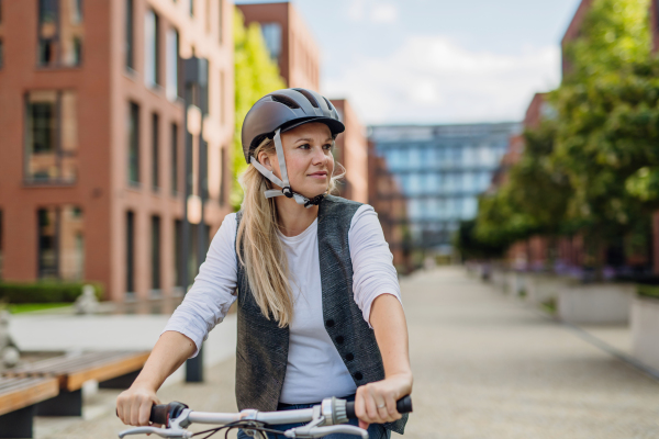 Beautiful middle-aged woman commuting through the city by bike. Female city commuter traveling from work by bike after a long workday.