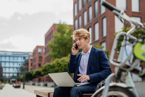 Portrait of businessman, freelancer or manager working outdoors in city park. Man with laptop on knees having video call. Concept of working remotely.