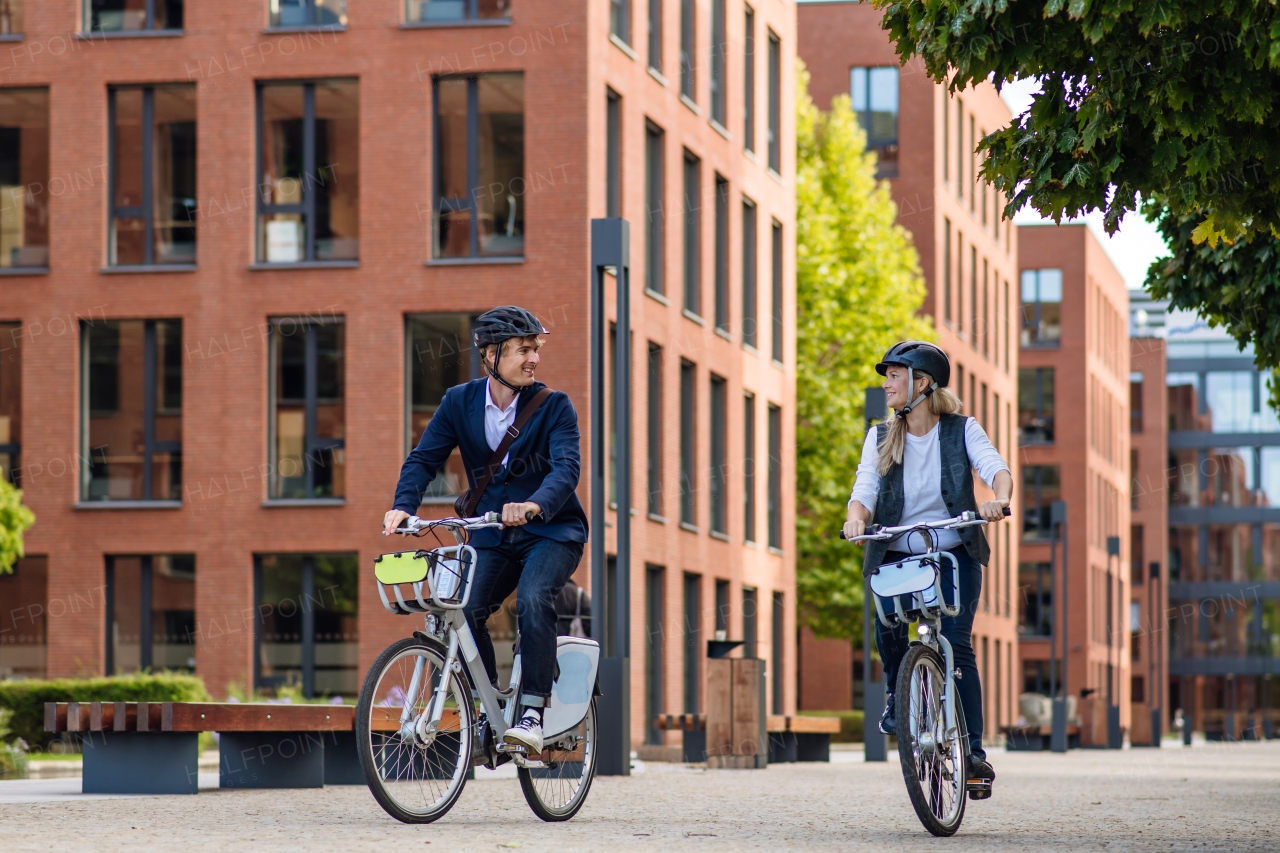 Spouses commuting through the city, riding bike on street. Middle-aged city commuters traveling from work by bike after a long workday. Husband and wife riding bikes in city.