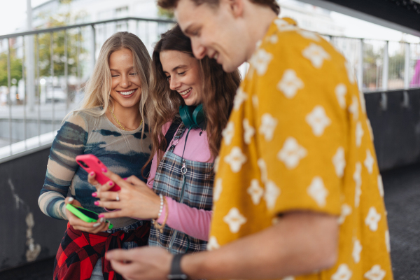 Generation z students hanging out together outdoors in the city. Young stylish zoomers are online, using smartphones, social media, taking selfies. Concept of power of friendship and social strength of gen Z. Low angle shot with copy space.