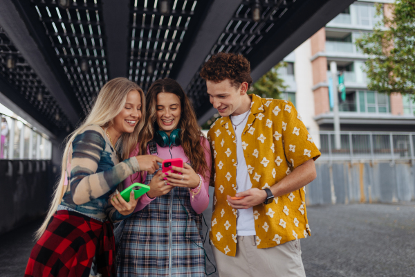 Generation z students hanging out together outdoors in the city. Young stylish zoomers are online, using smartphones, social media, taking selfies. Concept of power of friendship and social strength of gen Z.