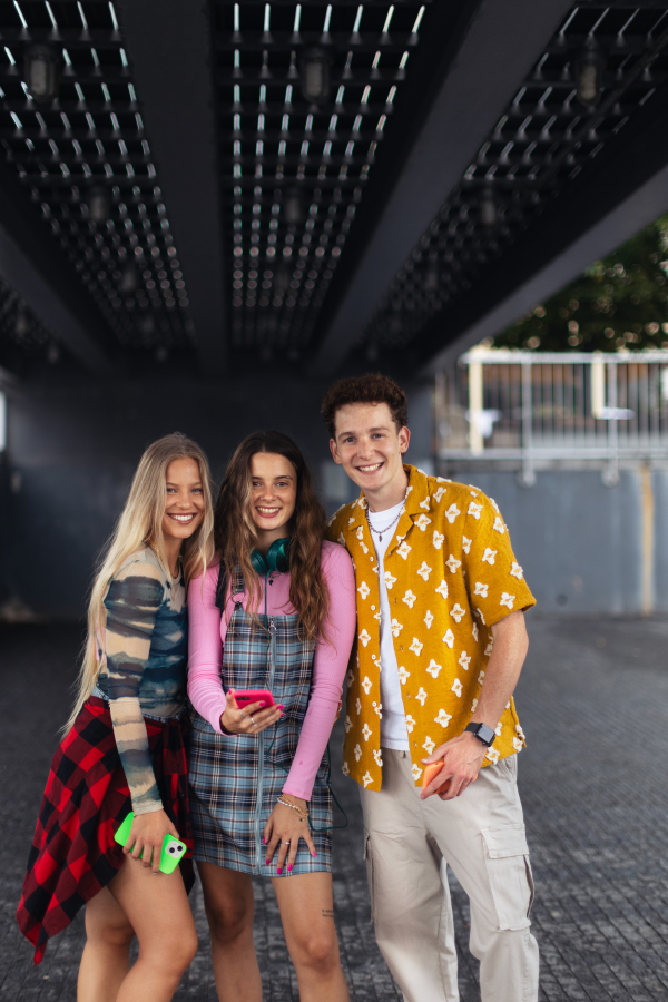 Generation z students hanging out together outdoors in the city. Young stylish zoomers are online, using smartphones, social media, taking selfies. Concept of power of friendship and social strength of gen Z.