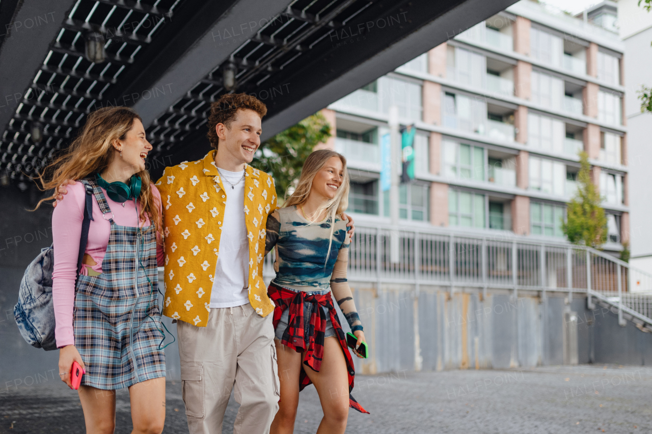 Generation z students hanging out together outdoors in the city. Young stylish zoomers are online, using smartphones, social media, taking selfies. Concept of power of friendship and social strength of gen Z.