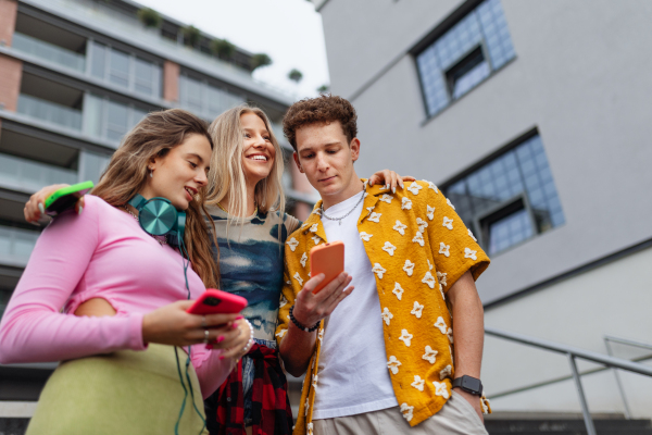 Generation z students hanging out together outdoors in the city. Young stylish zoomers are online, using smartphones, social media, taking selfies. Concept of power of friendship and social strength of gen Z.