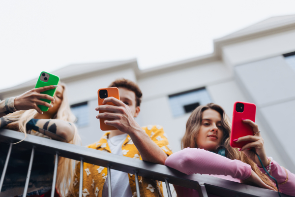 Generation z students hanging out together outdoors in the city. Young stylish zoomers are online, using smartphones, social media, taking selfies. Concept of power of friendship and social strength of gen Z.