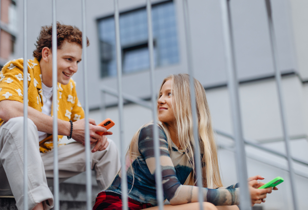 Young Gen Z students meeting outside in the city, sitting on the stairs. Love at first sight. Boy and girl feeling instant attraction.