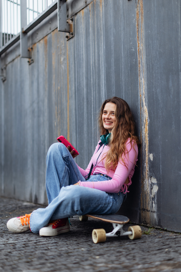 Portrait of generation z girl student sitting outdoors in the city. Student spending free time online and alone. Concept of gen Z as loneliest generation.