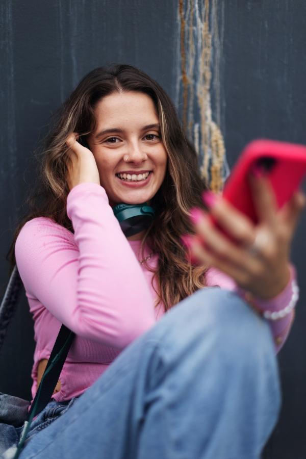 Portrait of generation z girl student sitting outdoors in the city. Student spending free time online and alone. Concept of gen Z as loneliest generation.