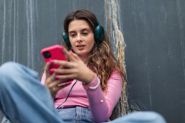 Portrait of generation z girl student sitting outdoors in the city. Student spending free time online and alone. Concept of gen Z as loneliest generation.