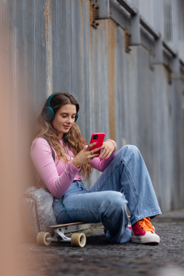 Portrait of generation z girl student sitting outdoors in the city. Student spending free time online and alone. Concept of gen Z as loneliest generation.