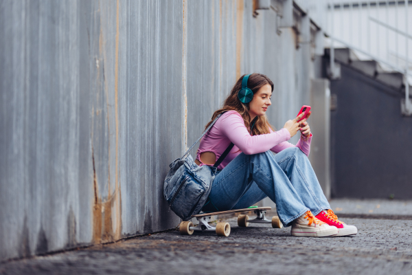 Portrait of generation z girl student sitting outdoors in the city. Student spending free time online and alone. Concept of gen Z as loneliest generation.