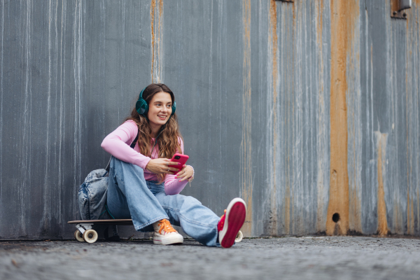 Portrait of generation z girl student sitting outdoors in the city. Student spending free time online and alone. Concept of gen Z as loneliest generation.