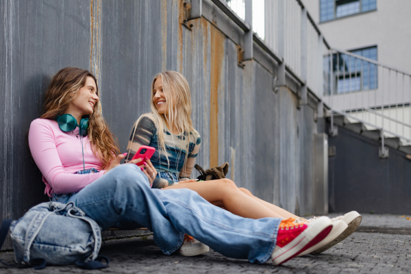 Young stylish generation Z girls studying together outdoors after school. Young female zoomers talking and gossiping during lunch break in the school. Concept of power of friendship and importance of education for gen Z.