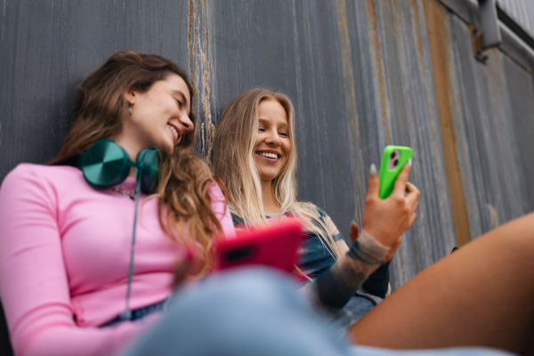 Young stylish generation Z girls spending time together outdoors after school. Young female zoomers talking and gossiping during lunch break in the school. Concept of power of friendship and importance of education for gen Z.