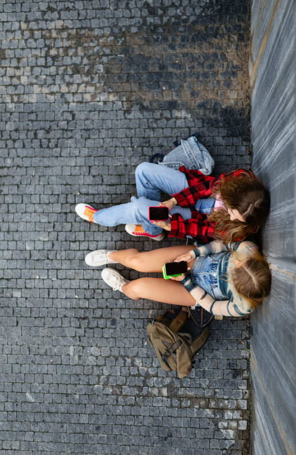 Top view of young stylish generation Z girls studying together outdoors after school. Young female zoomers talking and gossiping during lunch break in the school. Concept of power of friendship and importance of education for gen Z.