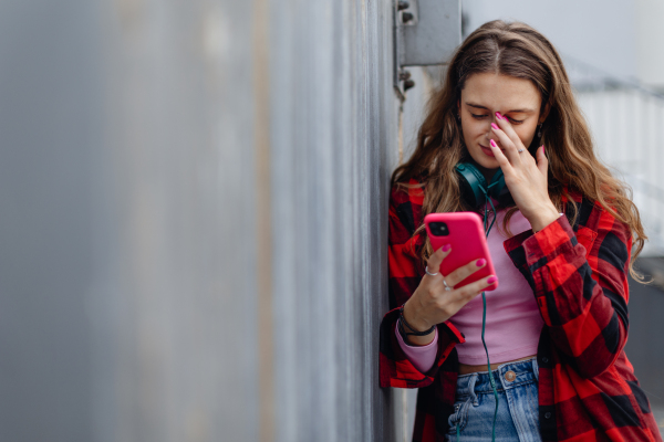 Gen Z girl outdoors in the city, feeling sad and anxious. Young zoomer student is alone. Concept of gen Z as loneliest generation.