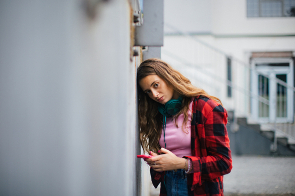 Gen Z girl outdoors in the city, feeling sad and anxious. Young zoomer student is alone. Concept of gen Z as loneliest generation.