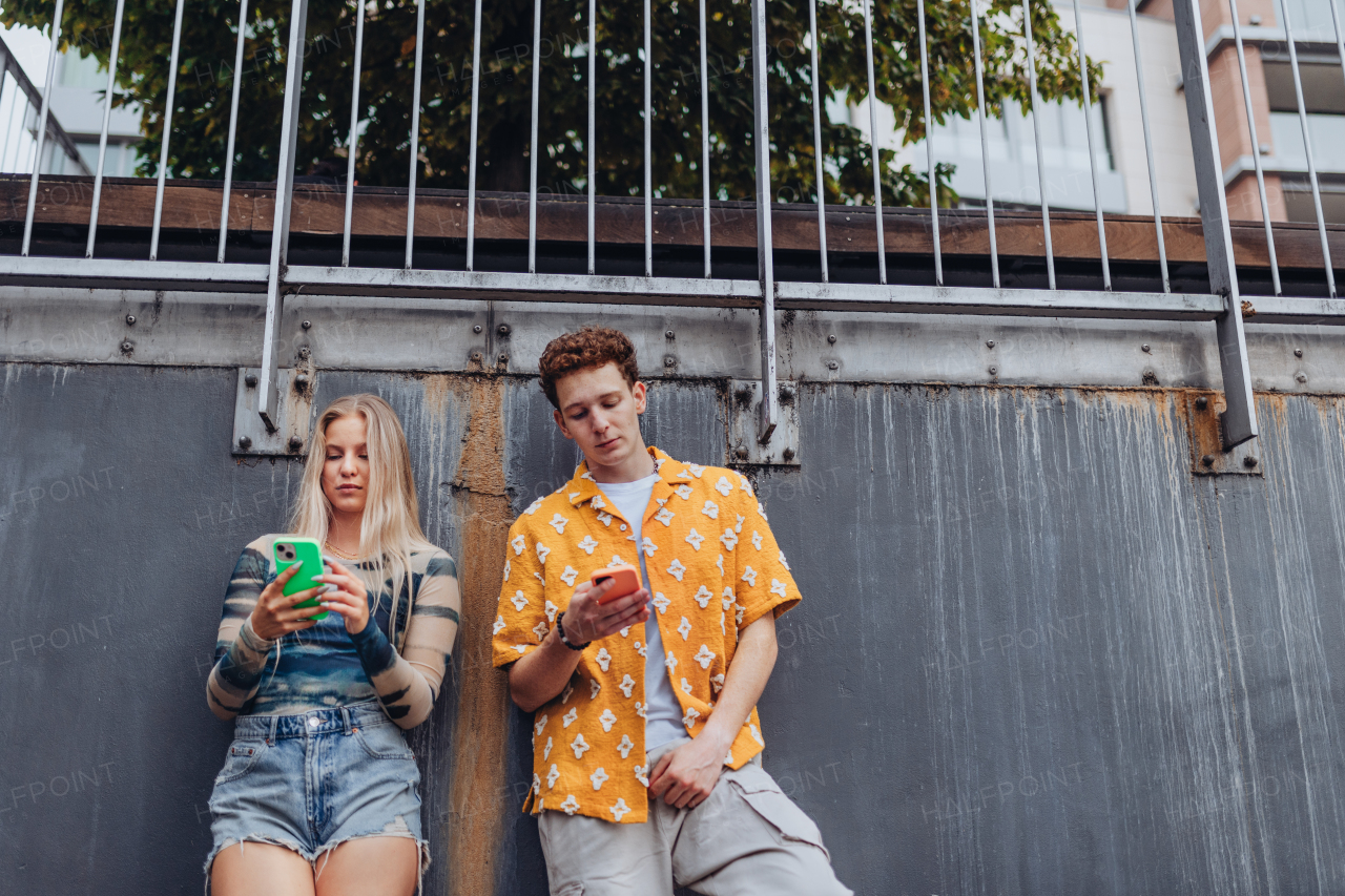 Portrait of generation z couple spending time outdoors in the city online. Students spending free time online, watching social media content. Concept of gen Z as loneliest generation.