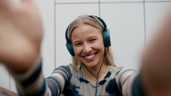 Video of a Generation Z girl student listening to music via headphones outdoors in the city. Student spending free time online and alone. Concept of gen Z as loneliest generation.