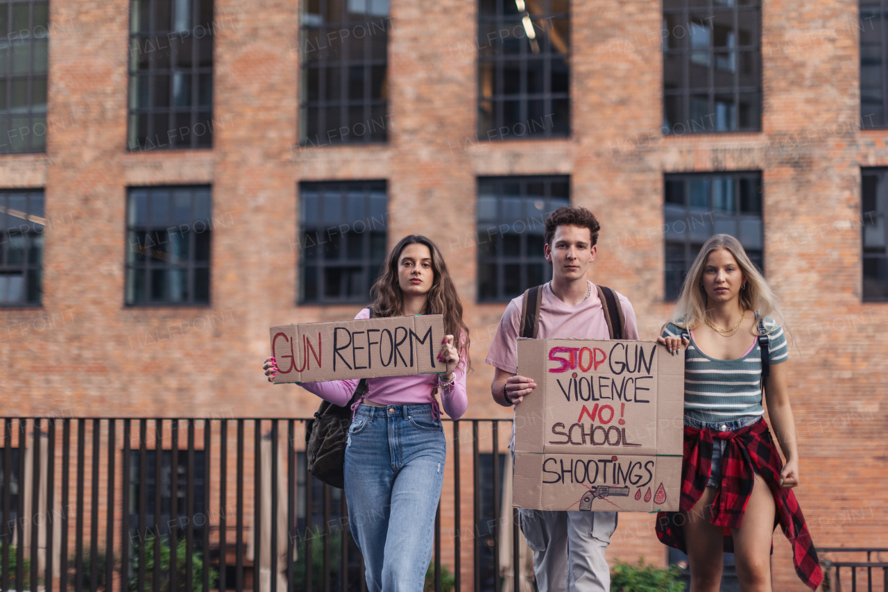 Generation Z activists with banners protesting on the street. Young students marching through the city demonstrate against climate change. Protesters demanding gun control, racial and gender equity. Concept of social strength of gen Z.