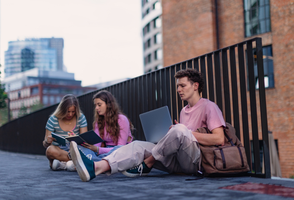 Group of generation Z students studying together outdoors after school. Young stylish zoomers working together on school project, preparing a presentation. Concept of power of friendship and importance of education of gen Z.