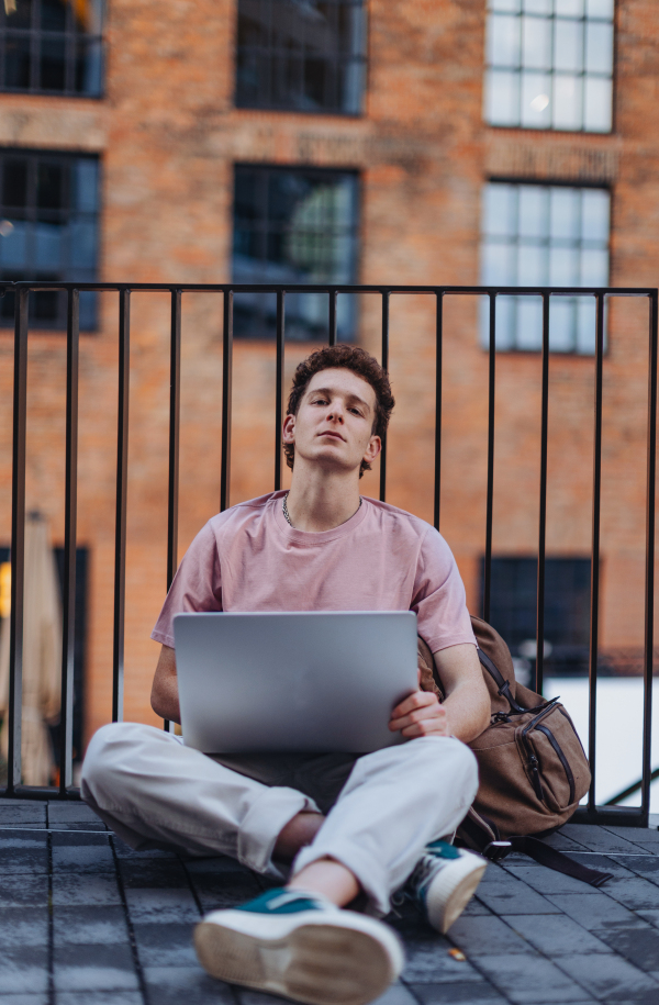 Gen Z student working on laptop after lecture on campus. Young stylish zoomer studiing outdoors. Concept of importance of education of gen Z.