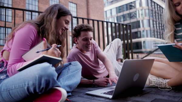 Group of generation Z students studying together outdoors after school. Young stylish zoomers working together on school project, preparing a presentation. Concept of power of friendship and importance of education of gen Z.