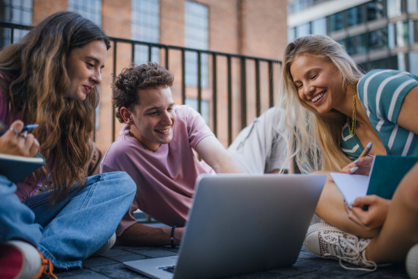 Group of generation Z students studying together outdoors after school. Young stylish zoomers working together on school project, preparing a presentation. Concept of power of friendship and importance of education of gen Z.