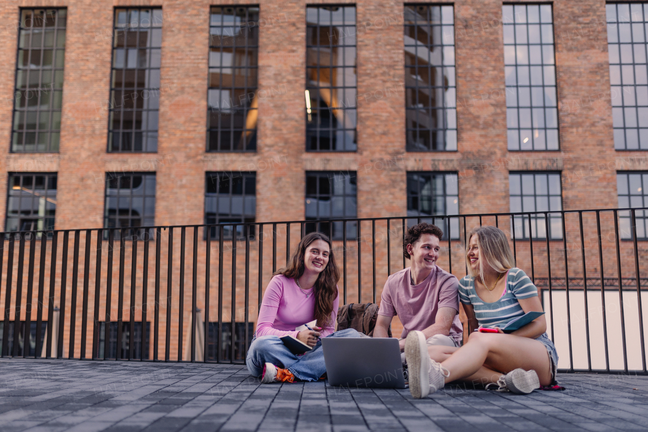 Young stylish generation Z students sitting s in front of school building. Young female zoomers talking and gossiping during lunch break in the school. Concept of power of friendship and importance of education for gen Z.