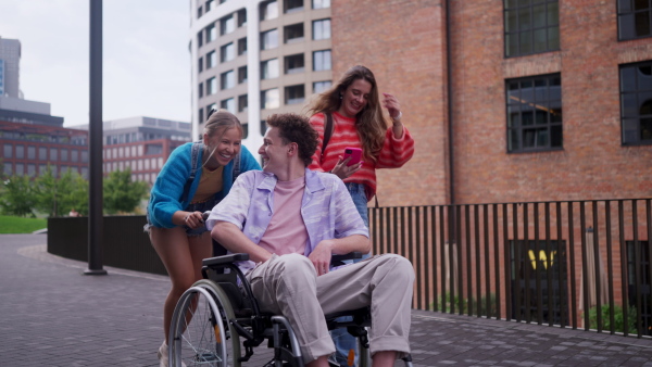 Handsome gen Z boy in a wheelchair with friends in the city. Inclusion, equality, and diversity among Generation Z.