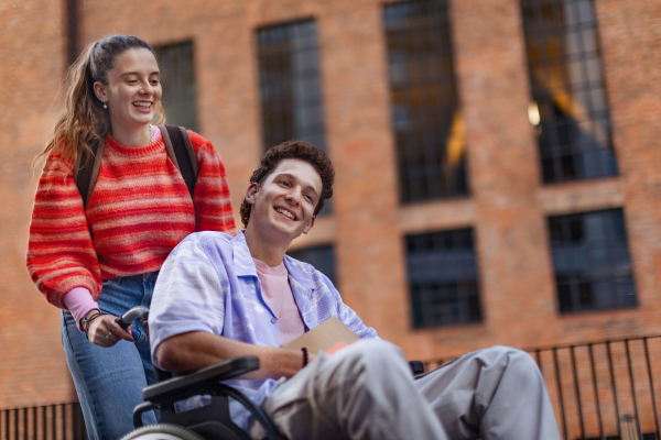 Handsome gen Z boy in a wheelchair with friend in the city. Inclusion, equality, and diversity among Generation Z.