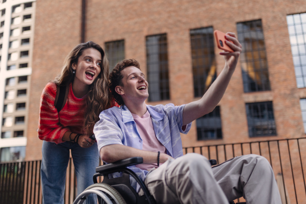 Handsome gen Z boy in a wheelchair with friends in the city. Inclusion, equality, and diversity among Generation Z.