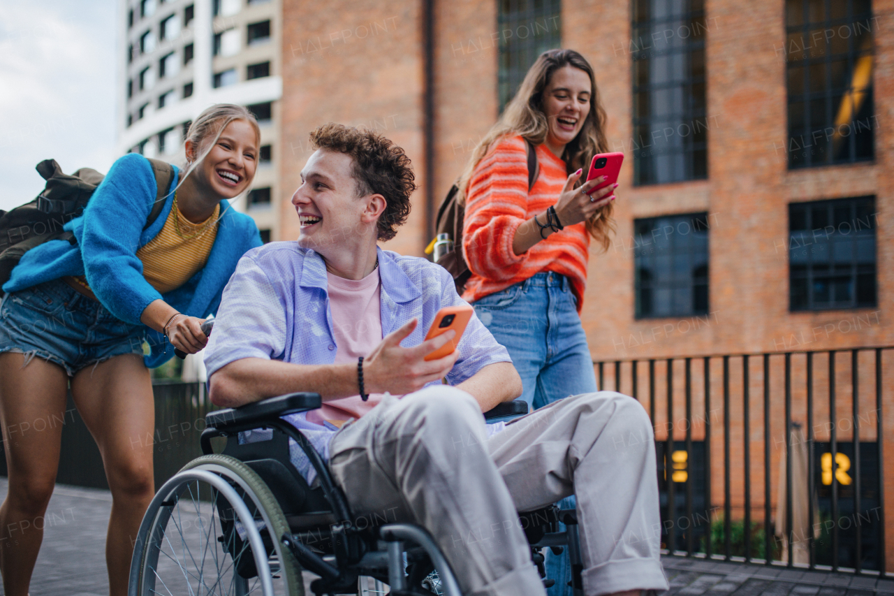 Handsome gen Z boy in a wheelchair with friends in the city. Inclusion, equality, and diversity among Generation Z.