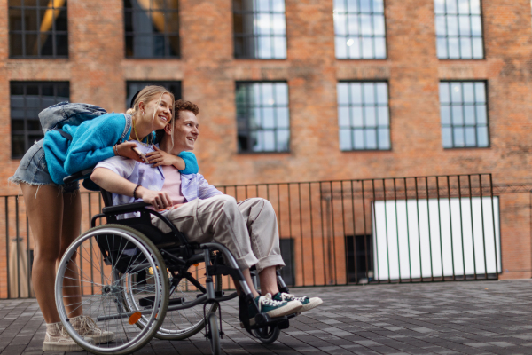 Hansome gen Z boy in a wheelchair with his girlfriends. Love with disability. Inclusion, equality, and diversity among Generation Z people.