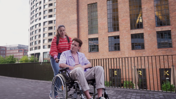 Handsome gen Z boy in a wheelchair with friend in the city. Inclusion, equality, and diversity among Generation Z.