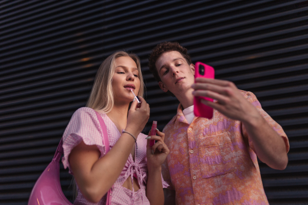 Gen Z couple in pink outfit taking selfie before going the cinema to watch movie. The young zoomer girl and boy watched a movie addressing the topic of women, her position in the world, and body image.