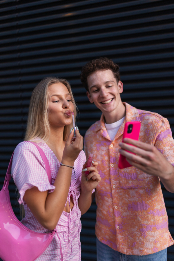 Gen Z couple in pink outfit taking selfie before going the cinema to watch movie. The young zoomer girl and boy watched a movie addressing the topic of women, her position in the world, and body image.