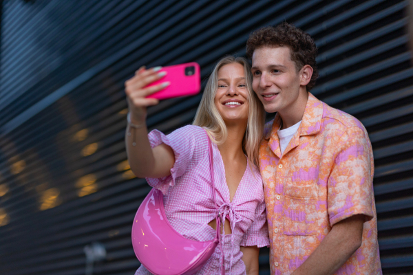 Gen Z couple in pink outfit taking selfie before going the cinema to watch movie. The young zoomer girl and boy watched a movie addressing the topic of women, her position in the world, and body image.