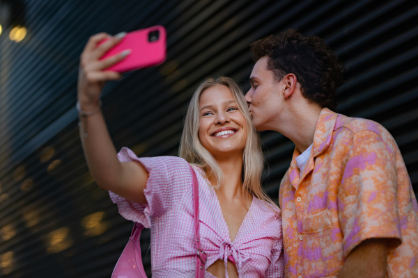 Gen Z couple in pink outfit taking selfie before going the cinema to watch movie. The young zoomer girl and boy watched a movie addressing the topic of women, her position in the world, and body image.