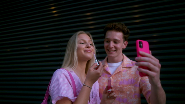 Gen Z couple in pink outfit taking selfie before going the cinema to watch movie. The young zoomer girl and boy watched a movie addressing the topic of women, her position in the world, and body image.